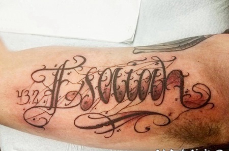 花体英文纹身 男生大臂上黑灰的花体英文纹身图片