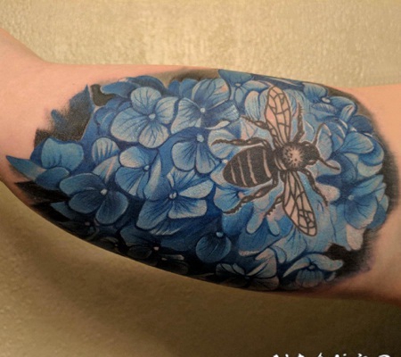 纹身图案花朵 男生大臂上彩色的花朵和蜜蜂纹身图片