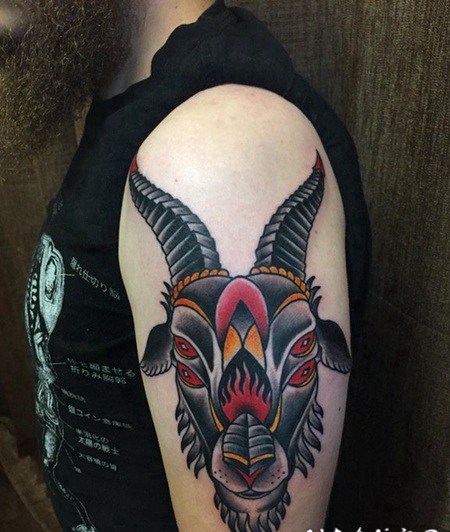 男子左手大臂上的传统风格四眼山羊头纹身图片