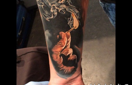 手臂写实风格的彩色人手和燃烧的火柴纹身图案