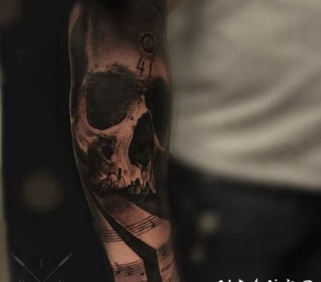 黑灰风格的骷髅和五线谱手臂纹身图案