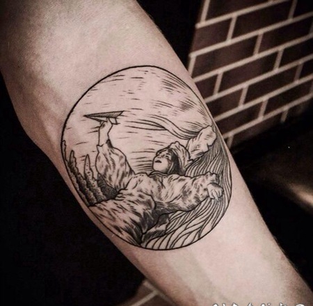 圆形雕刻风格男孩与纸飞机手臂纹身图案