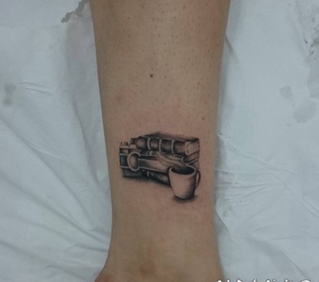 苍白的书和热气腾腾的茶杯脚踝纹身图案