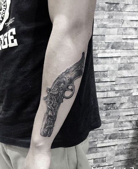 男子手臂上的枪纹身图案