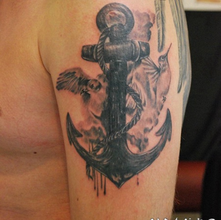 手臂黑色的船锚与鸟类纹身图案