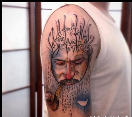 大臂彩色的吸烟管男子和字母纹身图案