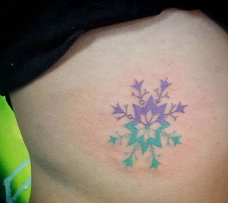 胸腔上紫色和绿色参半的雪花形状图案纹身