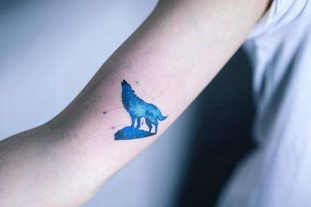 一只蓝色的狼站在山上吼叫的纹身图片