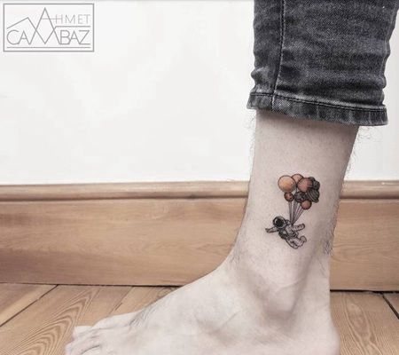 腿上的一个被气球带着飞的小宇航员纹身