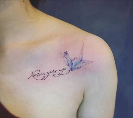 美女锁骨处唯美的折纸彩色千纸鹤和英文字母纹身