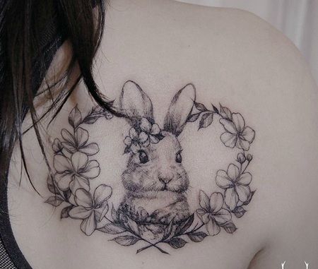女生肩部小白兔纹身，一只躲在花环里的小白兔