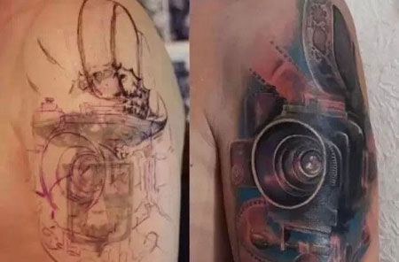 大臂上的遮盖相机纹身图案