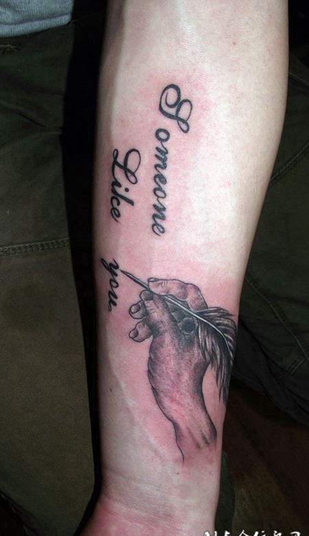 胳膊上拿着鹅毛笔的手纹身