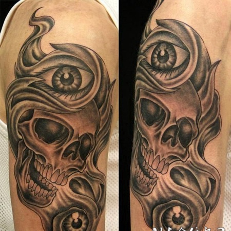 大臂上围着眼睛的骷髅头纹身图案