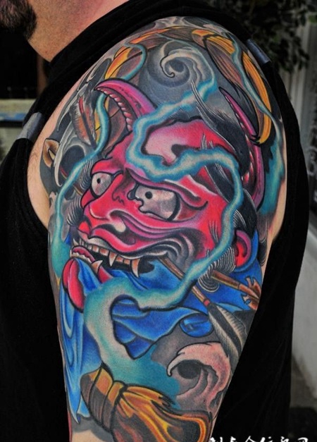 大臂上叼着箭支的般若纹身图案