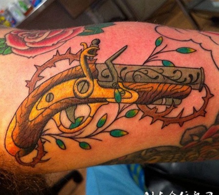 大臂上的木柄手枪纹身图案