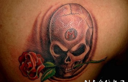 肩胛骨上叼着玫瑰花的骷髅头纹身图案