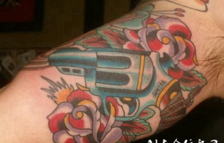 胳膊上的左轮枪与玫瑰纹身图案