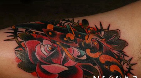 大臂上的玫瑰花手枪纹身图案