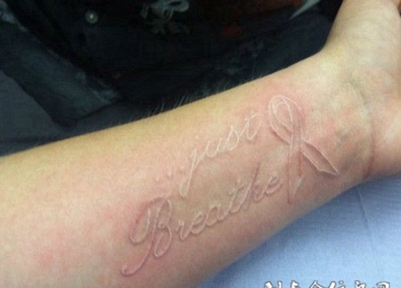 手臂上丝带和英文鸽子血纹身图案