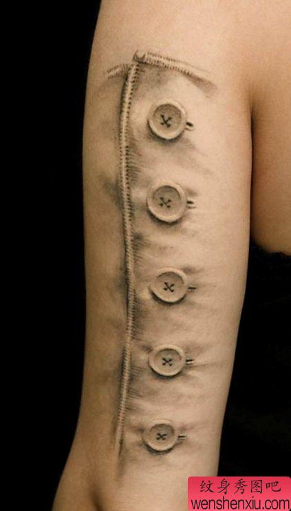 欣赏大臂上一幅逼真的纽扣纹身图案