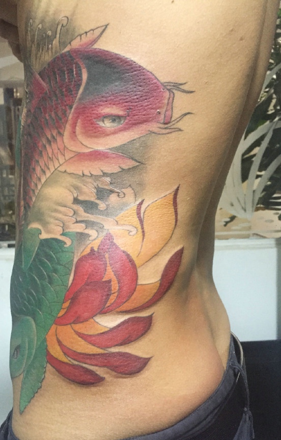 落在侧腰部的两条彩色大鲤鱼刺青
