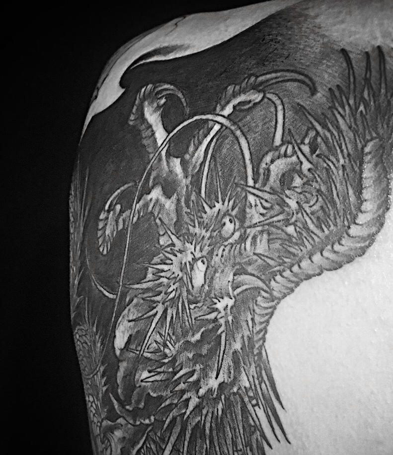 绕着大臂的黑白大邪龙纹身图案