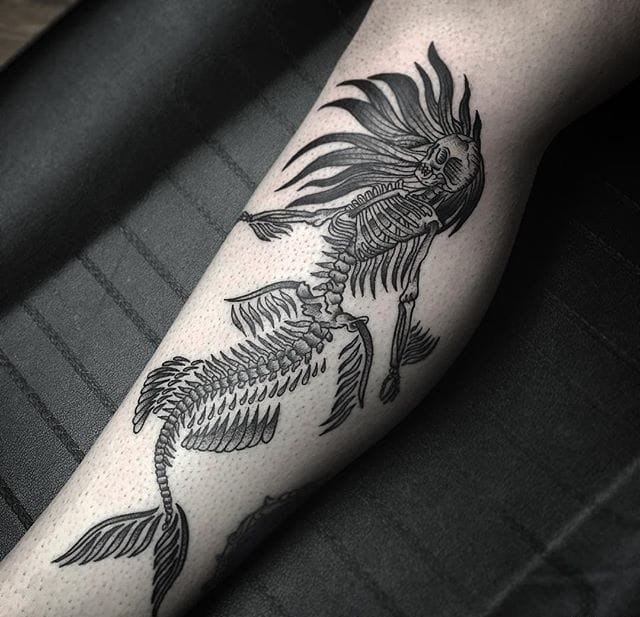 小腿上带有人脸的太阳纹身图案