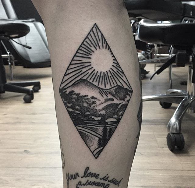 小腿上带有人脸的太阳纹身图案