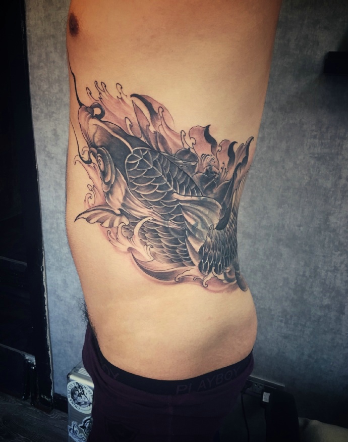 围绕着男生侧腰部的活跃鲤鱼纹身图案