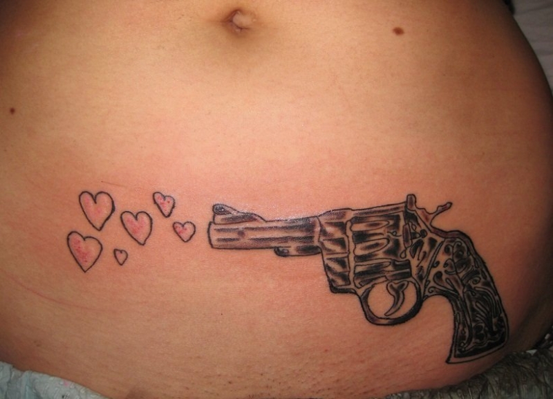 女孩大腿上的环形初边和手枪纹身图案