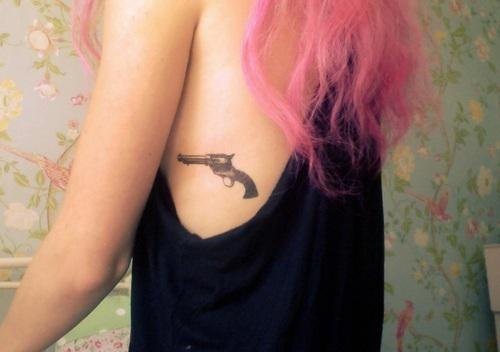 女孩大腿上的环形初边和手枪纹身图案