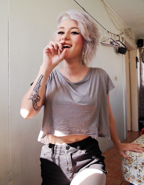 女孩大腿上的环形初边和手枪纹身图案