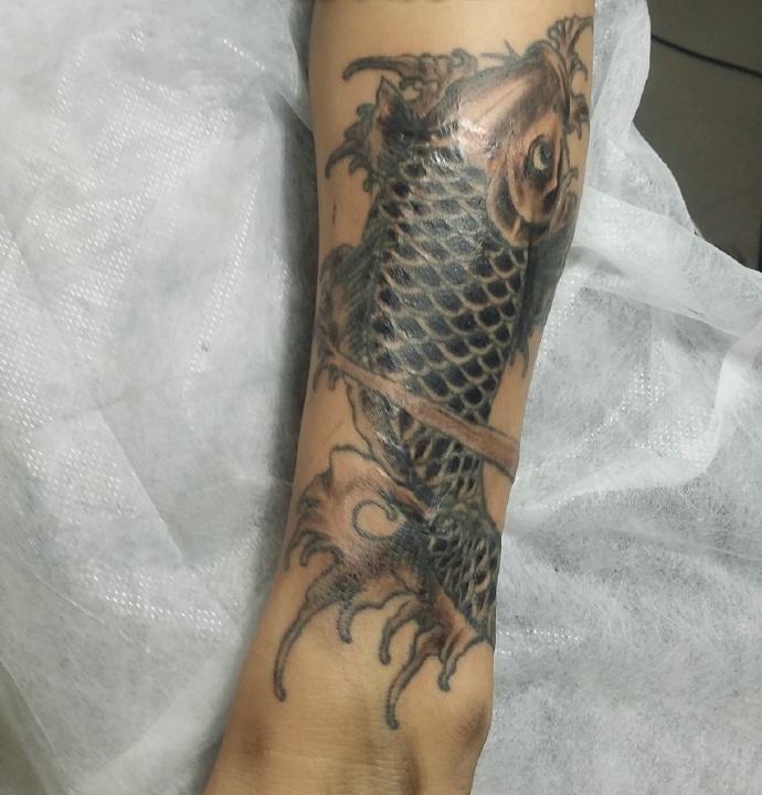 小腿部处着一条黑白鲤鱼纹身图案