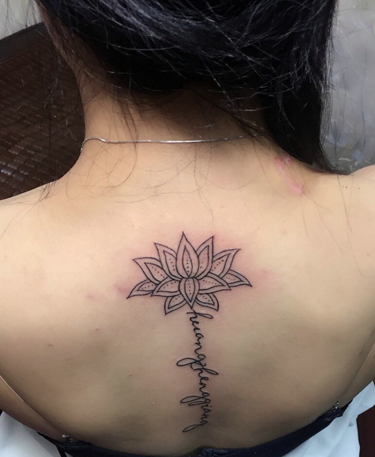 处在脊椎部莲花与英文的纹身图案
