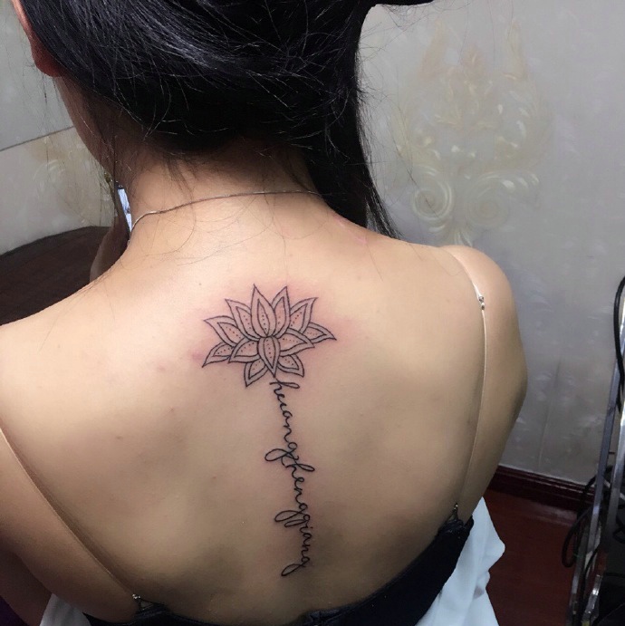 处在脊椎部莲花与英文的纹身图案