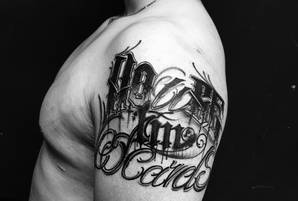 大臂花体英文纹身图案很显眼