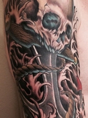 大臂上的邪恶骷髅头和船锚纹身