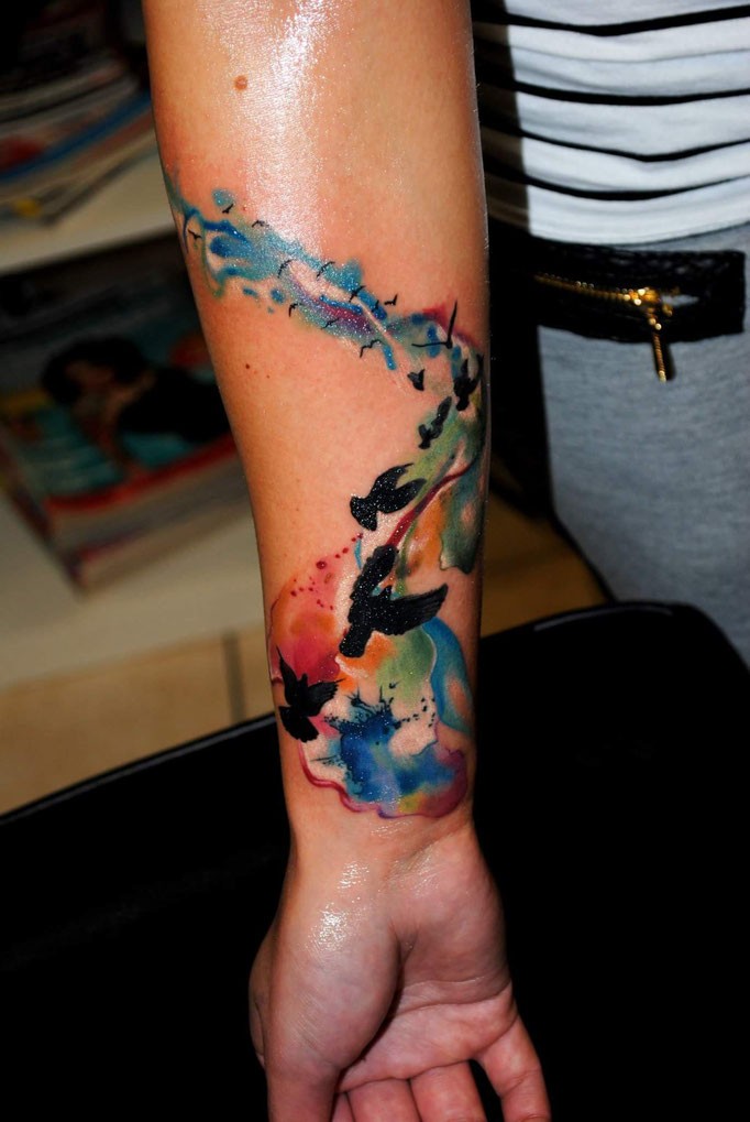 小臂成群的飞行黑色鸟与彩色云纹身图案