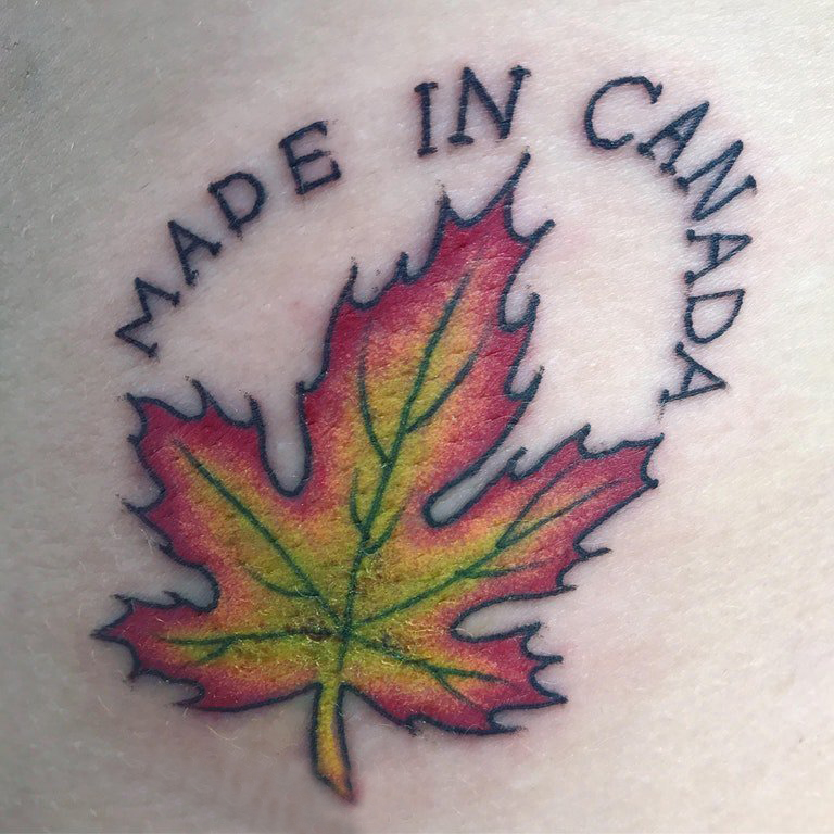 男生手臂上彩绘渐变英文单词和植物枫叶纹身图片