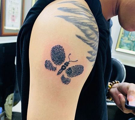 帅哥大臂上指纹拼组的蝴蝶纹身