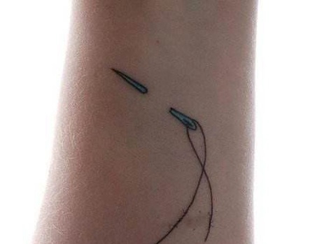 手臂上刺破皮肤的针线纹身