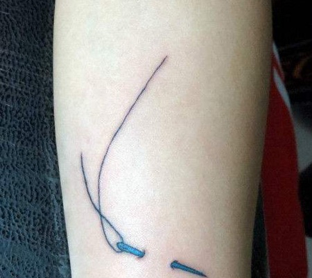 手臂处穿过皮肤的针线纹身