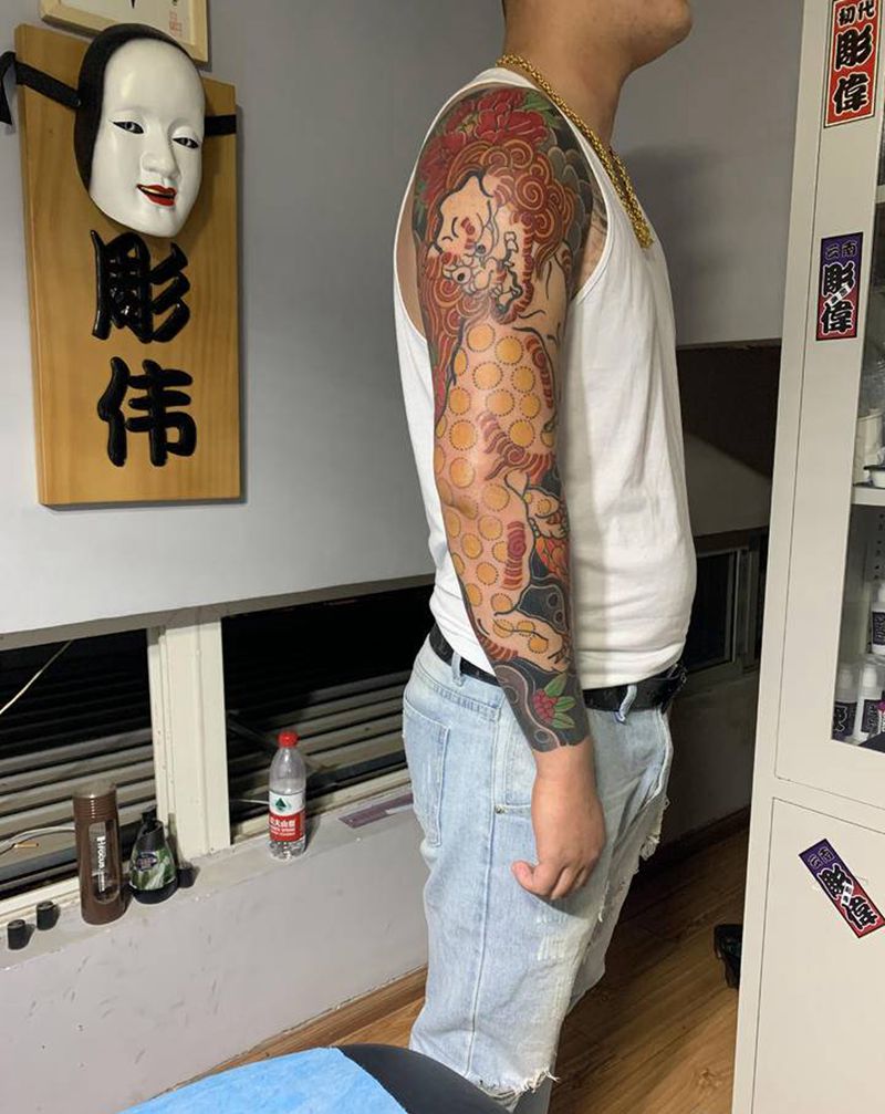 唐狮戏牡丹花臂纹身图片_手臂老传统纹身图案